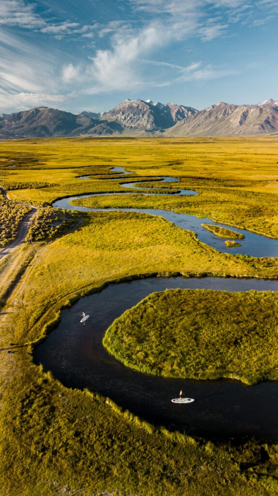 pexels-photo-3464632-3464632 Stunning drone view of a winding river through lush green plains and mountains.